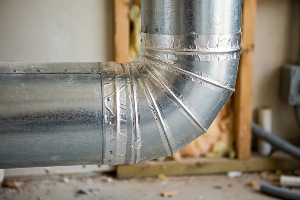 A sealed metal duct joint with neat foil sealing in a home utility room