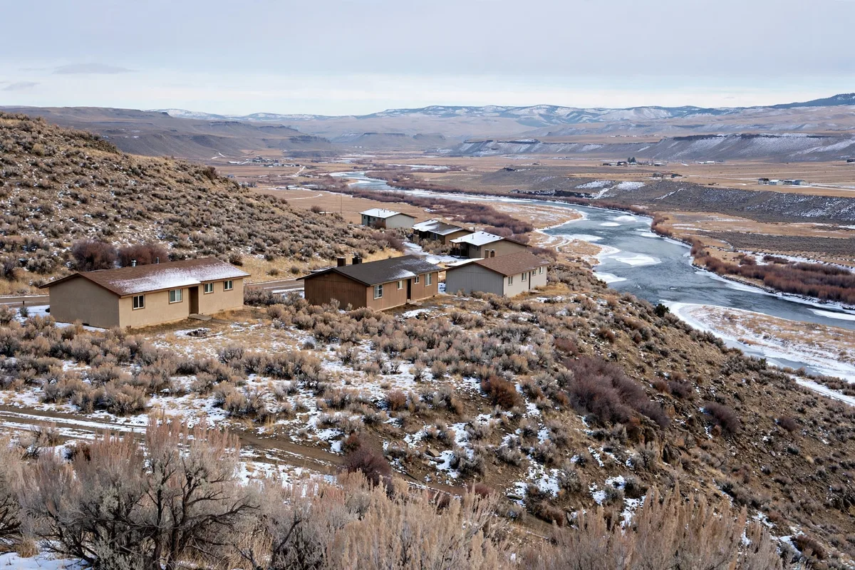Ranch houses on a sagebrush hillside above a river valley in winter in Green River