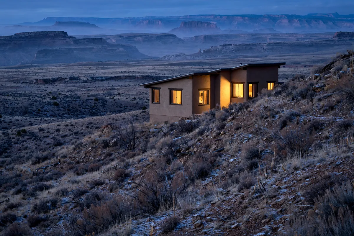 A house on a dry desert hillside at dusk with warm windows in Rock Springs